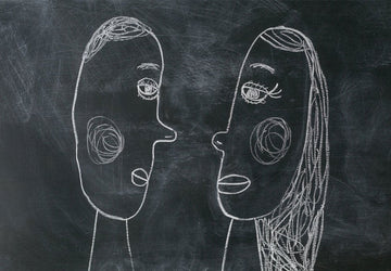 Two chalk-drawn face profiles facing each other on a dark chalkboard, representing the contrasting thinking styles of mom brain and dad brain