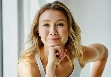 Rachel smiling warmly with her chin resting on her hand, wearing a white athletic top