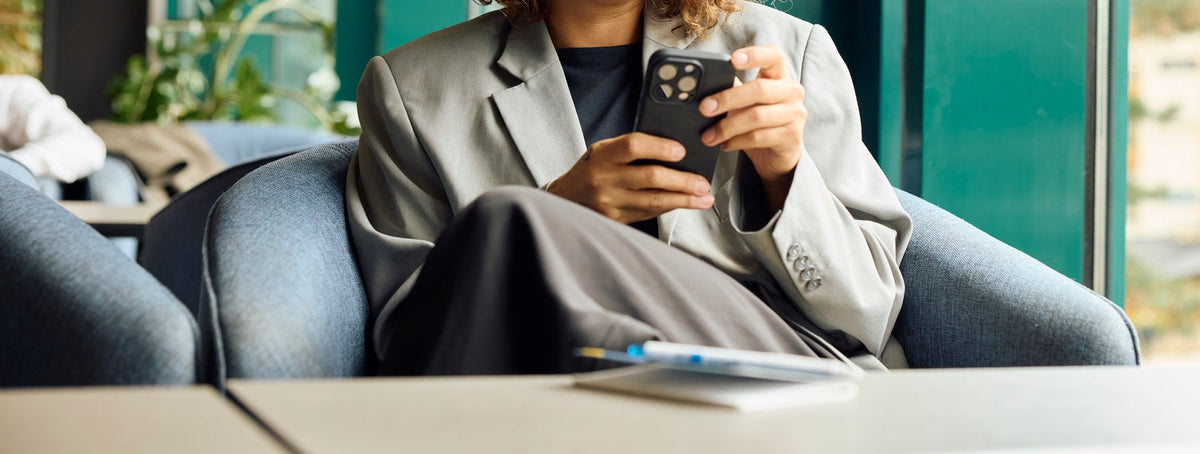 Woman in a blazer checking her phone in an office lounge